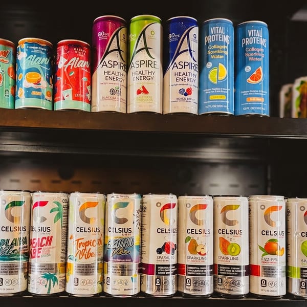 A store shelf displays various colorful energy drinks, including Alani, Aspire, Vital Proteins, and Celsius brands.