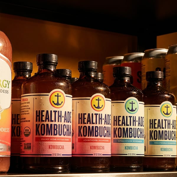 Bottles of Synergy Guava Goddess, Health-Ade Kombucha, and cans of SAP! Soda on a shelf.